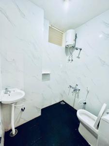 a white bathroom with a sink and a toilet at Darshan Arrive & Revive Homestay. in Kushālnagar
