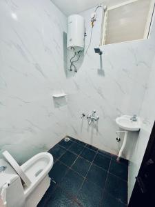 a white bathroom with a toilet and a sink at Darshan Arrive & Revive Homestay. in Kushālnagar