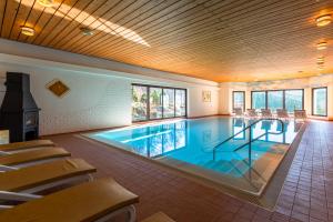 ein großer Pool mit Stühlen und Tischen in einem Gebäude in der Unterkunft RelaxHotel Tannenhof in Sasbachwalden