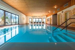 a swimming pool with blue water in a building with windows at RelaxHotel Tannenhof in Sasbachwalden