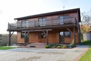 een houten huis met een balkon en een veranda bij Nad Stawem in Powidz