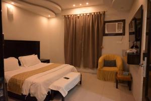 Habitación de hotel con cama y silla en بيوتات الزير en Al Baha