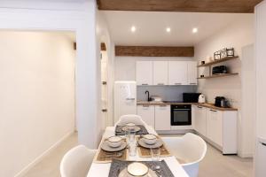 een witte keuken met een tafel en witte stoelen bij "L'historique" - Charmant appartement en centre-ville historique in Chambéry