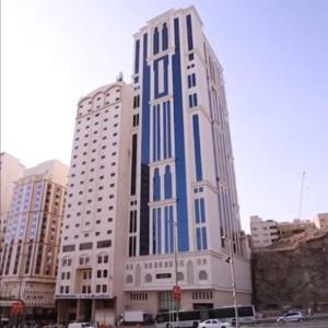 a tall blue and white building in a city at Al Ebaa Hotel in Makkah