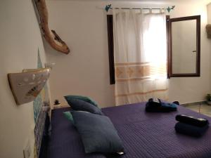 a bedroom with a purple bed with pillows and a window at Cuccuru Relax - A IUN Q9882 in Orosei