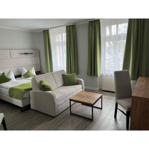 ein Wohnzimmer mit einem Sofa und einem Bett in der Unterkunft Hotel und Restaurant Kranichsberg in Woltersdorf