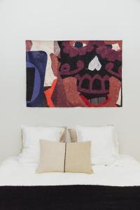 ein Bett mit weißen Kissen und ein Gemälde darüber in der Unterkunft LuxuryApartmentSoulforCity in Gent