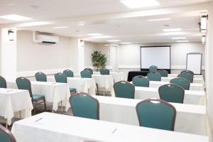 une salle de conférence avec des tables et des chaises blanches et un tableau blanc dans l'établissement Rodd Moncton, à Moncton