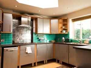 a kitchen with stainless steel cabinets and green tiles at Pass the Keys Funky Garden House in Chiswick in London