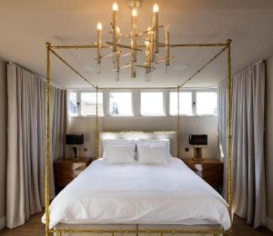 a bedroom with a white bed with a gold frame at Downs Cottage in Deal