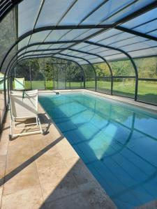 a swimming pool with a pergola and a chair at Colombier du château in Vitry-la-Ville