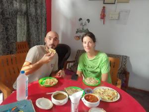 un hombre y una mujer sentados en una mesa comiendo pizza en Khajuraho Dreams Homestay, en Khajurāho