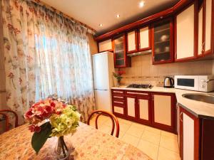 a kitchen with a table with a vase of flowers on it at Apartments near the Exhibition Centre in Kyiv