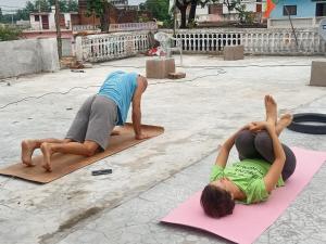 dos personas haciendo yoga en esterillas en la calle en Khajuraho Dreams Homestay, en Khajurāho