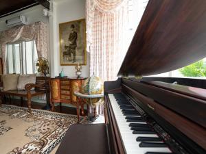 een woonkamer met een piano en een bank bij RoomQuest Rim Praya Dinsor Road in Bangkok