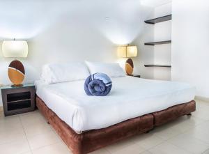Santorini Villas Santa Marta في سانتا مارتا: غرفة نوم عليها سرير مع وردة زرقاء