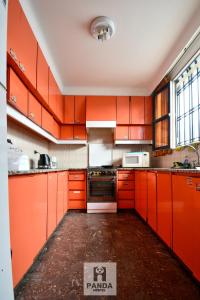 an orange kitchen with orange cabinets and appliances at Panda Hostel Mendoza in Mendoza