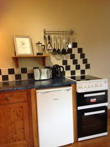 La cocina está equipada con fogones y horno blanco y negro. en Ty Twt - complete holiday home en Llandysul