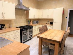 a kitchen with white cabinets and a wooden table at Villa with Park Views close to Liverpool Centre in Liverpool