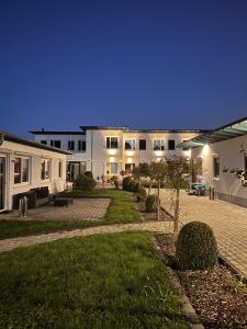 a large white building with a courtyard at night at Hotel Burgholz in Stepprath
