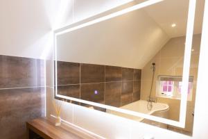 a bathroom with a tub and a sink and a mirror at Pavilion Orpington in Foots Cray