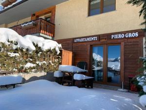 un edificio con mesas cubiertas de nieve frente a un restaurante en Appartamenti & Wellness Piero Gros, en Sauze dʼOulx