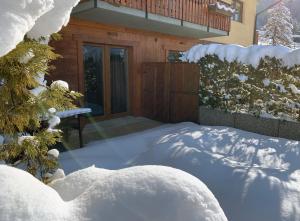 un patio cubierto de nieve con una casa en Appartamenti & Wellness Piero Gros en Sauze dʼOulx