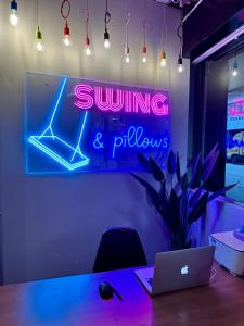 a neon sign in a room with a desk with a laptop at Swing & Pillows @ Beach Street in George Town +35 photos