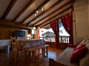 Una sala de estar con una mesa y sillas y un televisor. en Charmant appart 4/5 pers au pied des pistes avec balcon, Wifi, parking, animaux OK - FR-1-505-65, en Notre-Dame-de-Bellecombe