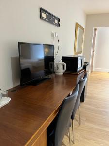 a wooden desk with a flat screen tv and chairs at Park View Rooms in Edinburgh
