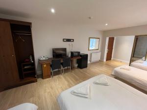 a room with two beds and a desk with a television at Park View Rooms in Edinburgh