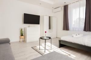 Un dormitorio con una cama y una mesa con una flor. en Stílusos lakás ingyenes parkolással, en Debrecen