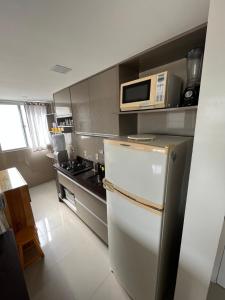 eine Küche mit einem weißen Kühlschrank und einer Mikrowelle in der Unterkunft Apto 301 in Caruaru