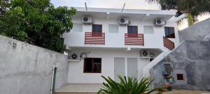ein weißes Gebäude mit roten Fenstern und einem Zaun in der Unterkunft Casa en Mahahual cerca de la playa D1 in Mahahual