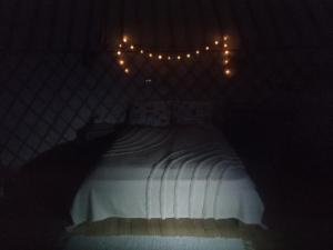 a bedroom with a white bed with lights on it at Jurtafarm Ráckeve - a nomád luxus in Ráckeve