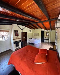 1 dormitorio con 1 cama grande de color rojo y bañera en Estancia De La Campiña, en Nono