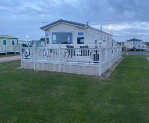 una pequeña casa con porche y valla en L&g FAMILY HOLIDAYS MILLFIELDS 6 BERTH FAMILYS ONLY AND THE LEAD PERSON MUST BE OVER 30s, en Ingoldmells