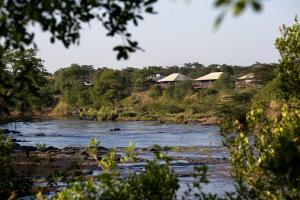 Un río con casas a un lado. en Neptune Mara Rianta Luxury Camp - All Inclusive. en Masai Mara