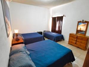 a bedroom with two beds and a dresser with a mirror at Casa Ferriño in Cuatrociénegas de Carranza