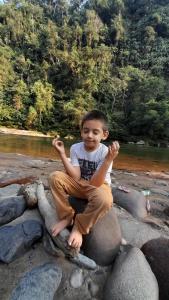 Ein kleiner Junge, der auf einem Felsen neben einem Fluss sitzt. in der Unterkunft PlayaSelva EcoLodge in Archidona