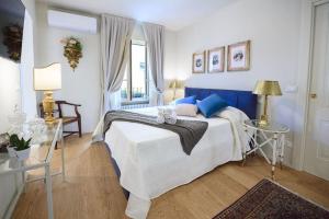 1 dormitorio con 1 cama blanca grande con almohadas azules en Corte Paolina - charming courtyard inside Lucca, en Lucca