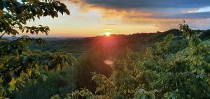 um pôr do sol nas montanhas com o pôr do sol em Olivea em Dobrovo