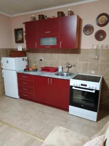 a kitchen with red cabinets and a sink and a refrigerator at Jovanovic in Topola