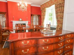 a dining room with red walls and a wooden dresser at Plas Cerrig Hall, Crossways Road in Mold