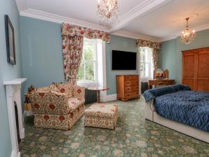 a bedroom with a bed and a chair and a tv at Plas Cerrig Hall, Crossways Road in Mold