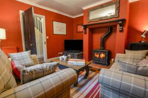 a living room with orange walls and a wood stove at Brook House in Woodbridge