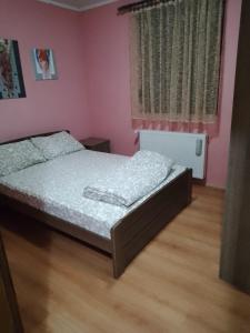 Topola的住宿－Jovanovic，卧室配有一张床铺,位于一间粉红色墙壁的房间
