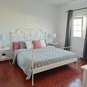 ein weißes Bett mit rosa Kissen im Schlafzimmer in der Unterkunft Casa Mar y Lava in El Golfo