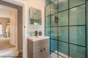a bathroom with a sink and a glass shower at Duck Cottage - Grade II Listed cottage, village location, nr Holt in Letheringsett