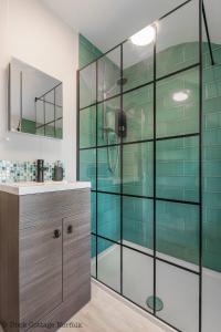 a glass shower in a bathroom with a sink at Duck Cottage - Grade II Listed cottage, village location, nr Holt in Letheringsett